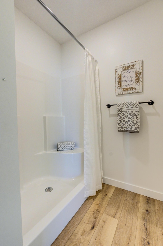 bathroom featuring baseboards, hardwood / wood-style flooring, and a shower with curtain