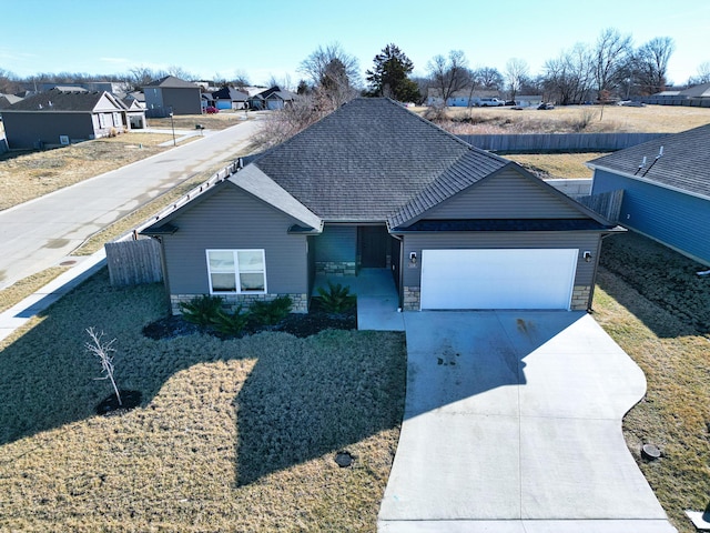 ranch-style house with a shingled roof, concrete driveway, a garage, a residential view, and stone siding