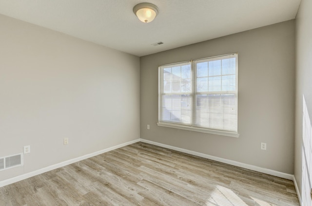 unfurnished room featuring visible vents, light wood-style flooring, and baseboards