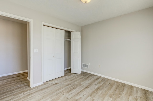 unfurnished bedroom featuring light wood-style floors, a closet, visible vents, and baseboards