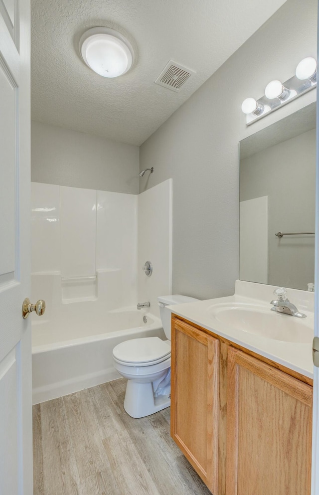 bathroom with visible vents, toilet, wood finished floors, a textured ceiling, and vanity