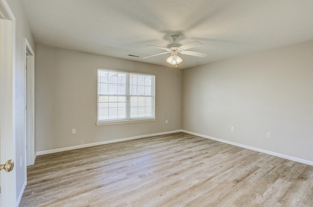 spare room with baseboards, a ceiling fan, visible vents, and light wood-style floors