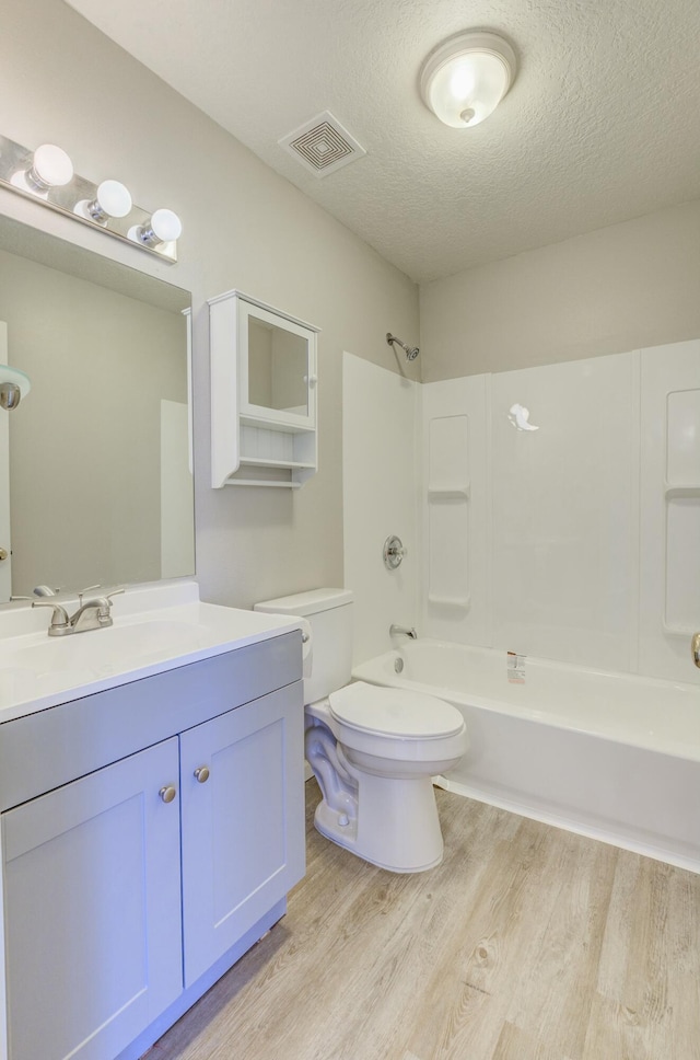 full bathroom featuring visible vents, toilet, washtub / shower combination, a textured ceiling, and wood finished floors