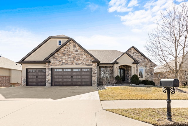 french country style house with an attached garage, driveway, a front yard, and stucco siding