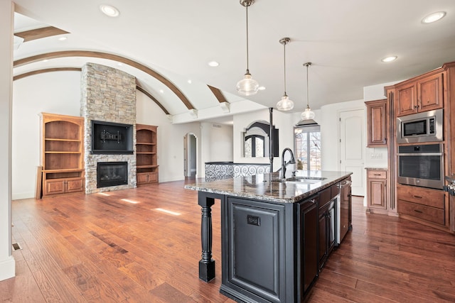 kitchen with lofted ceiling, appliances with stainless steel finishes, dark wood-type flooring, and a sink