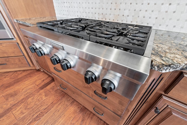 details featuring tasteful backsplash, stone countertops, and brown cabinets