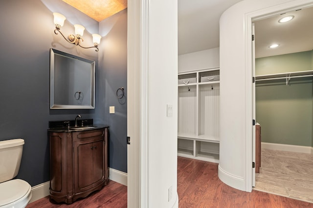 bathroom with vanity, wood finished floors, toilet, and baseboards