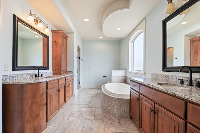 bathroom with a garden tub, two vanities, a sink, and stone tile floors