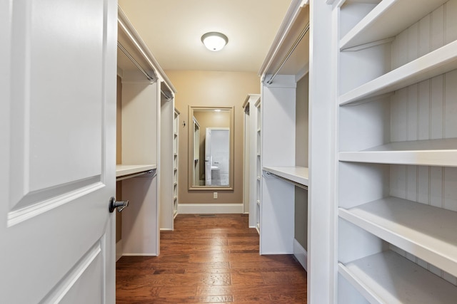 walk in closet with dark wood-style floors