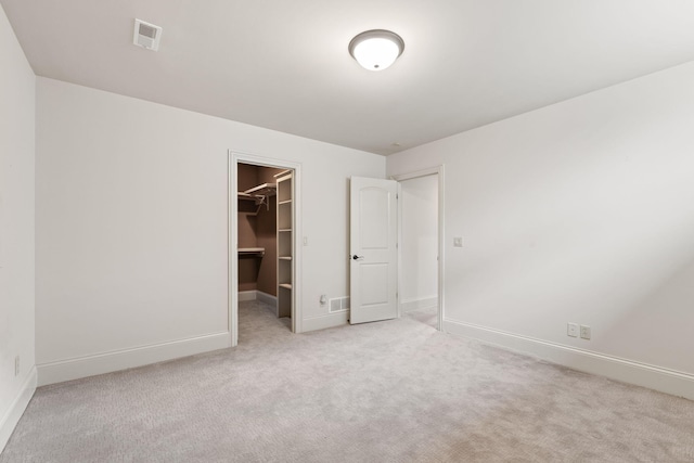 unfurnished bedroom with carpet flooring, visible vents, baseboards, a closet, and a walk in closet