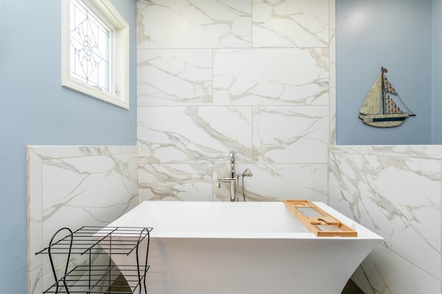 bathroom with a soaking tub and tile walls