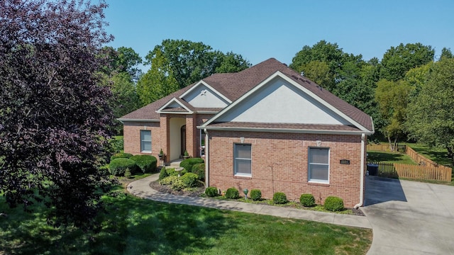 view of front of property with driveway, brick siding, a front yard, and fence