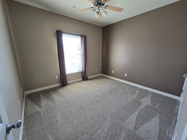 carpeted spare room with visible vents, baseboards, and a ceiling fan