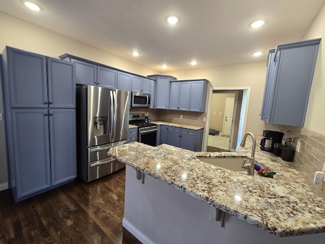 kitchen with appliances with stainless steel finishes, a peninsula, light stone counters, and a kitchen bar