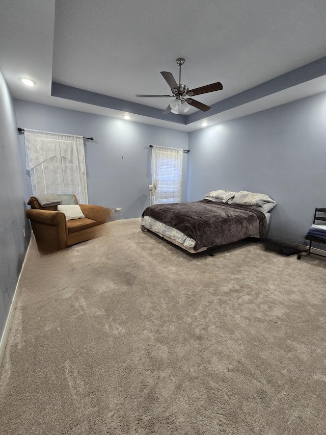 bedroom featuring ceiling fan, carpet floors, and a tray ceiling