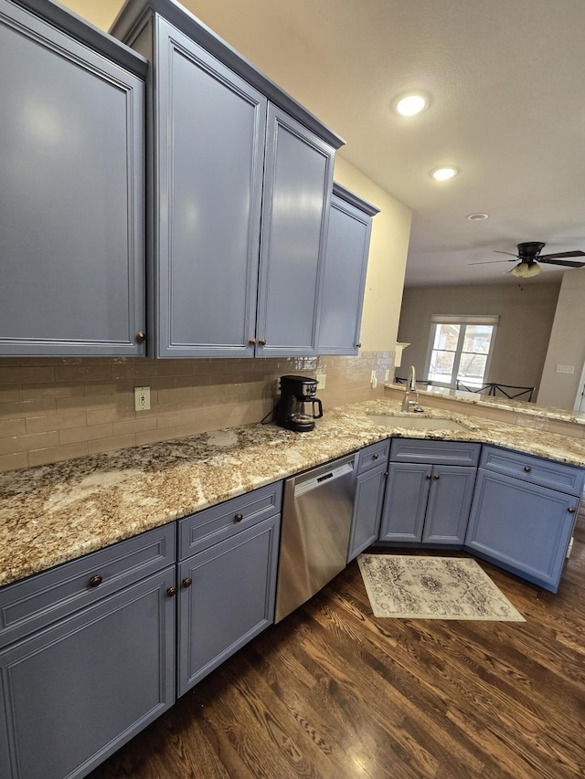 kitchen featuring tasteful backsplash, dishwasher, light stone counters, dark wood-type flooring, and a sink