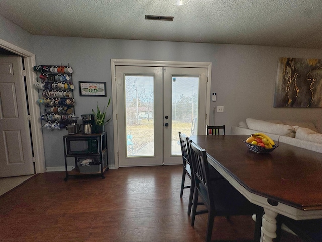 dining area featuring french doors, dark wood finished floors, visible vents, a textured ceiling, and baseboards