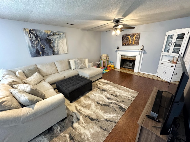 living room featuring visible vents, a ceiling fan, wood finished floors, a textured ceiling, and a fireplace