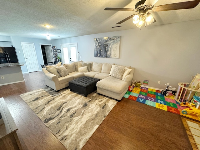 living room featuring baseboards, ceiling fan, wood finished floors, a textured ceiling, and french doors