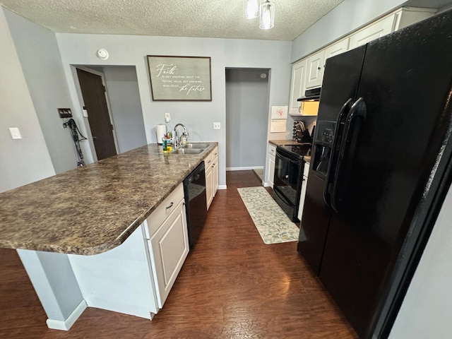 kitchen featuring a textured ceiling, dark wood-type flooring, a sink, black appliances, and dark countertops