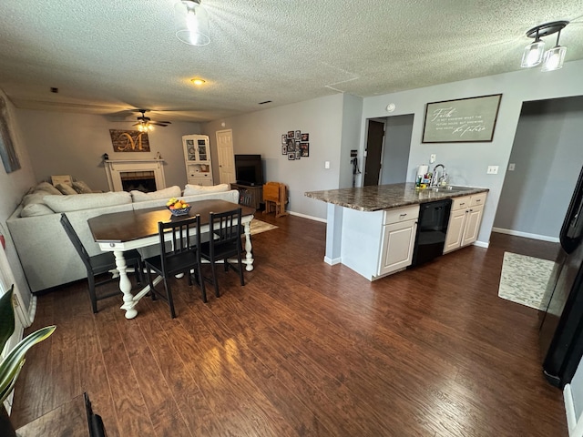 dining room featuring a textured ceiling, baseboards, dark wood-style flooring, and a tiled fireplace