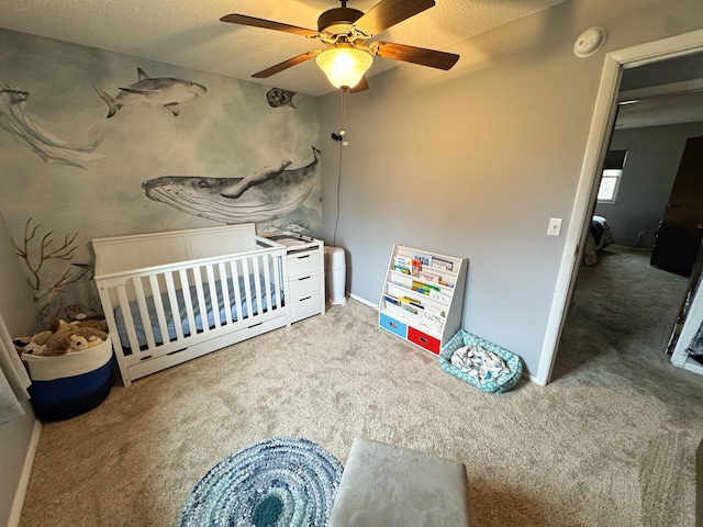 carpeted bedroom with a nursery area, ceiling fan, and a textured ceiling