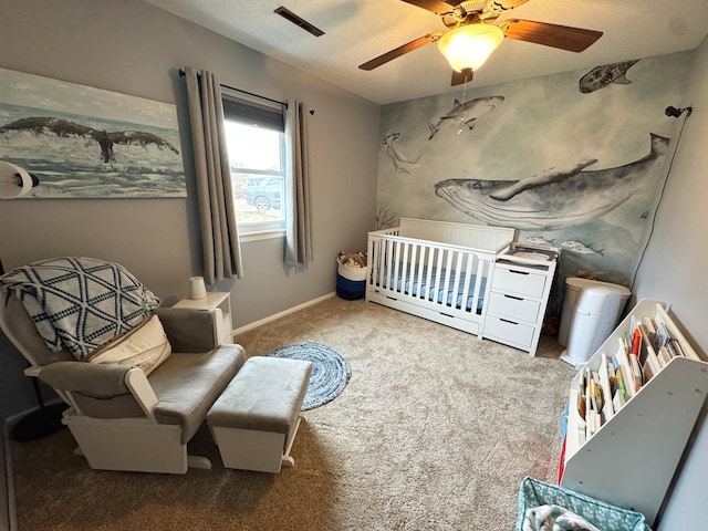 bedroom featuring ceiling fan, visible vents, baseboards, a crib, and carpet