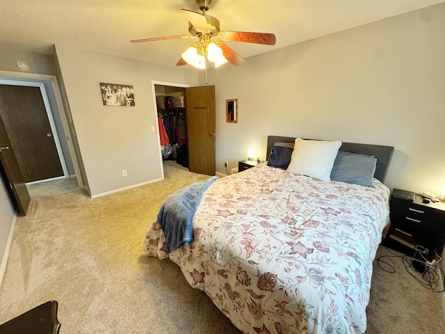 carpeted bedroom featuring baseboards, ceiling fan, a walk in closet, a textured ceiling, and a closet