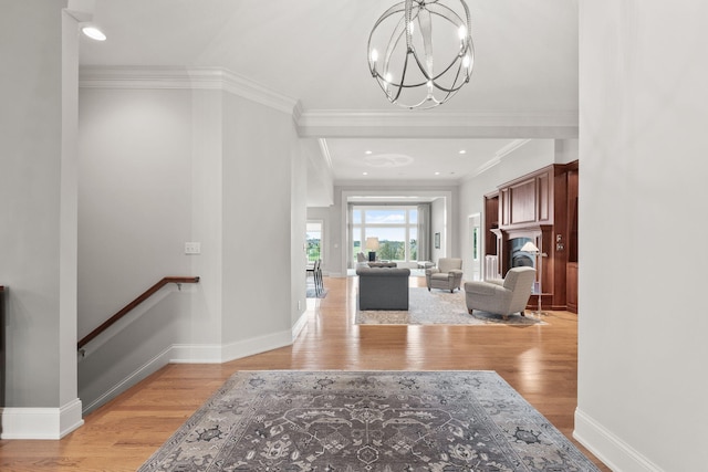 foyer entrance featuring baseboards, an inviting chandelier, crown molding, light wood-style floors, and recessed lighting