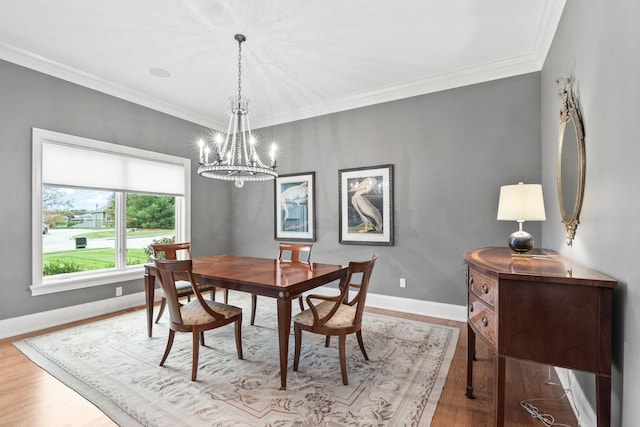 dining area featuring a notable chandelier, baseboards, crown molding, and wood finished floors