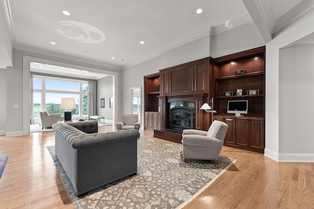 living area featuring light wood-type flooring, baseboards, ornamental molding, and a glass covered fireplace