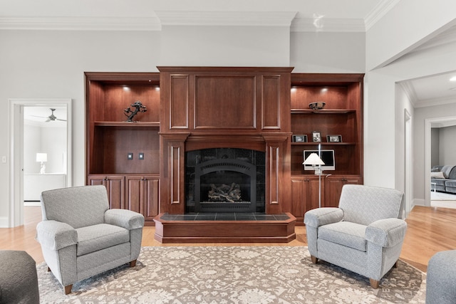 living area with light wood finished floors, ornamental molding, a tile fireplace, and baseboards