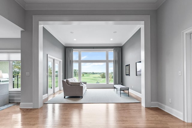 sitting room with light wood-type flooring, baseboards, a wealth of natural light, and ornamental molding