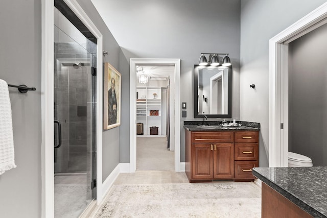 bathroom featuring baseboards, toilet, tile patterned flooring, vanity, and a shower stall