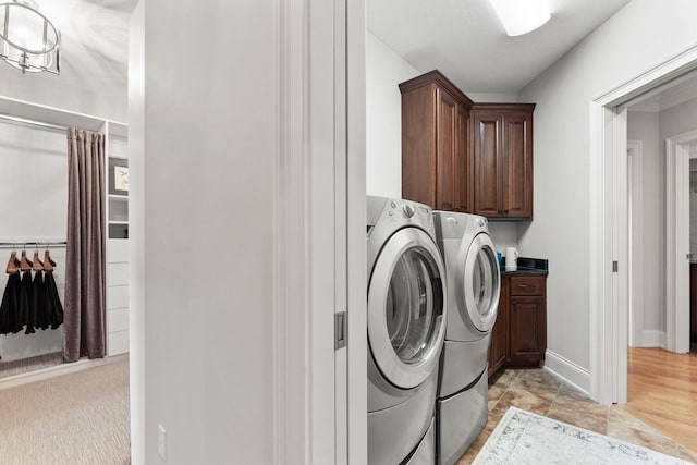 laundry area featuring independent washer and dryer, cabinet space, and baseboards