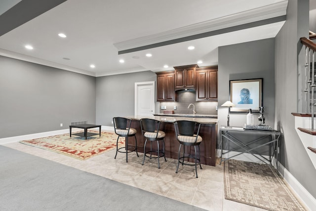 kitchen featuring crown molding, tasteful backsplash, recessed lighting, a kitchen breakfast bar, and baseboards