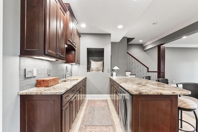 kitchen featuring decorative backsplash, wine cooler, a breakfast bar area, light stone countertops, and a sink