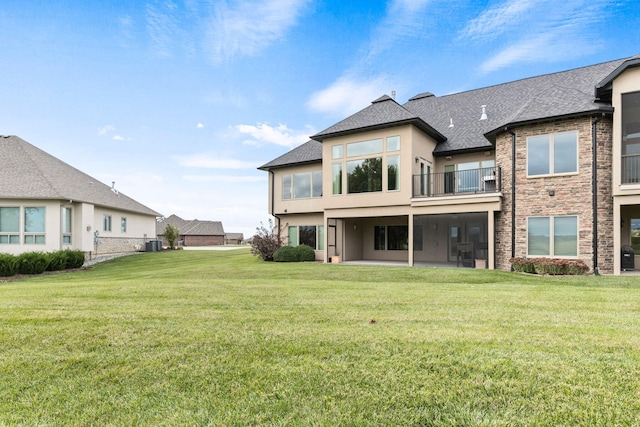 back of house with roof with shingles, central AC, a lawn, and stucco siding