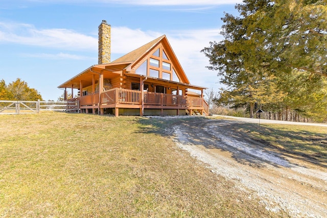 view of front of property featuring a chimney, a front yard, fence, log siding, and a wooden deck