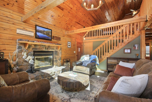 living area with wood ceiling, wooden walls, stairway, and a stone fireplace