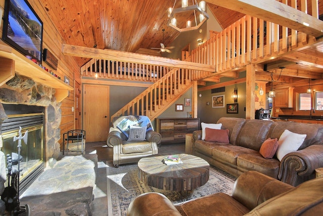 living area featuring a stone fireplace, high vaulted ceiling, wooden ceiling, beamed ceiling, and stairs