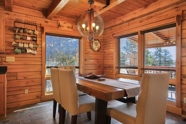 dining space featuring wood walls, wood ceiling, beam ceiling, stone tile flooring, and an inviting chandelier