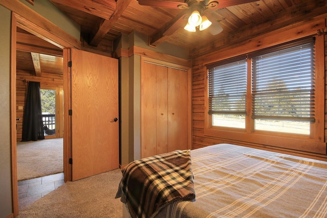 bedroom with a closet, wood ceiling, carpet flooring, wooden walls, and beamed ceiling