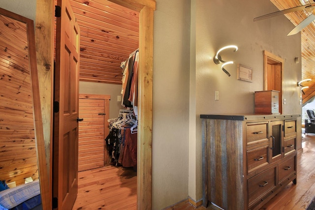 hallway with light wood-type flooring, wooden ceiling, and lofted ceiling