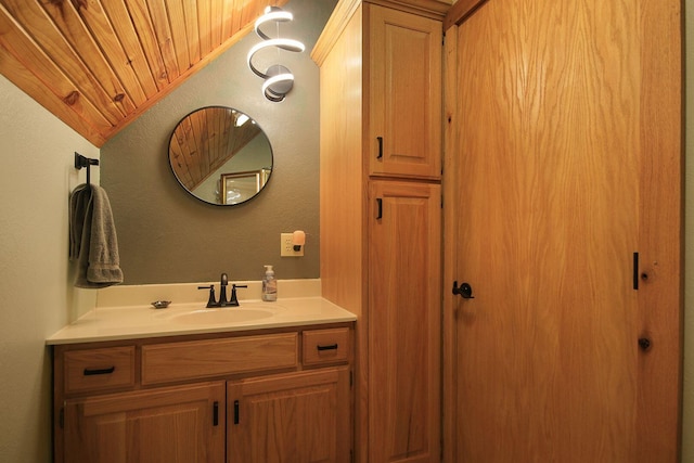 bathroom featuring lofted ceiling, a textured wall, and vanity