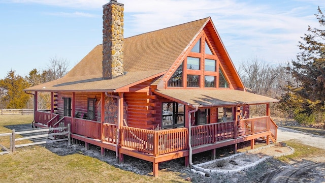 back of house with roof with shingles, fence, a chimney, and log siding