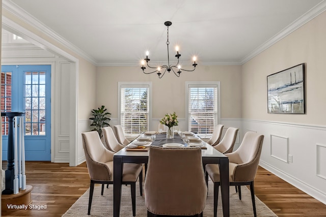 dining area with ornamental molding, a decorative wall, and wood finished floors