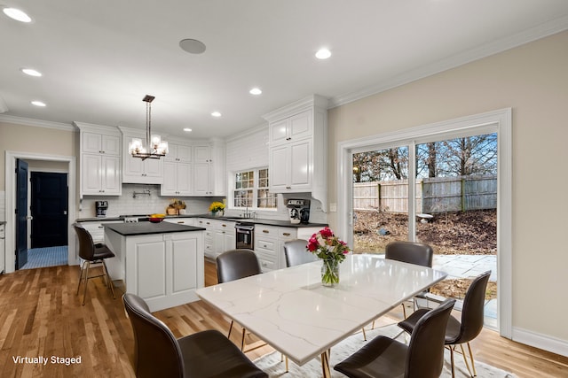 kitchen with a kitchen island, white cabinets, backsplash, dark countertops, and crown molding