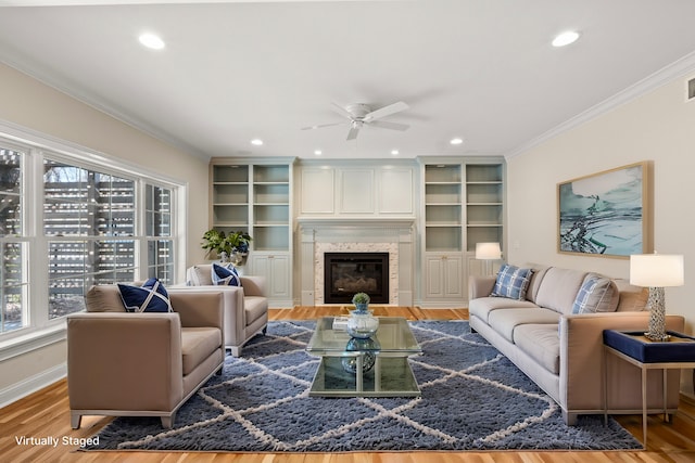 living room featuring recessed lighting, ornamental molding, a high end fireplace, wood finished floors, and baseboards