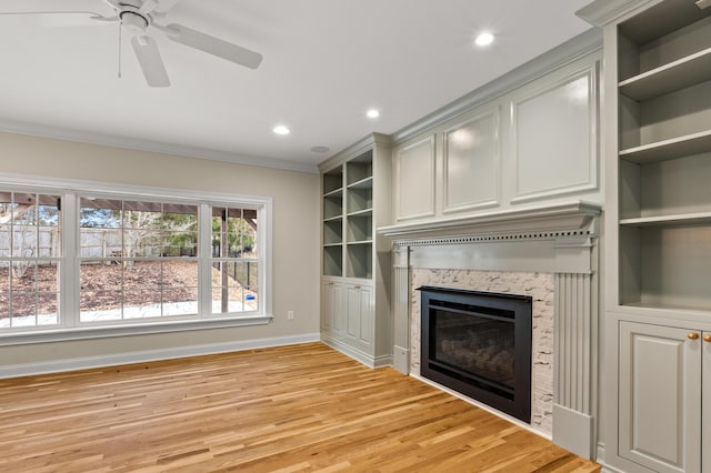 unfurnished living room featuring ornamental molding, a premium fireplace, light wood-style flooring, and baseboards